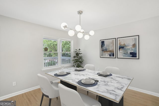 dining area with light wood-style floors, a chandelier, and baseboards