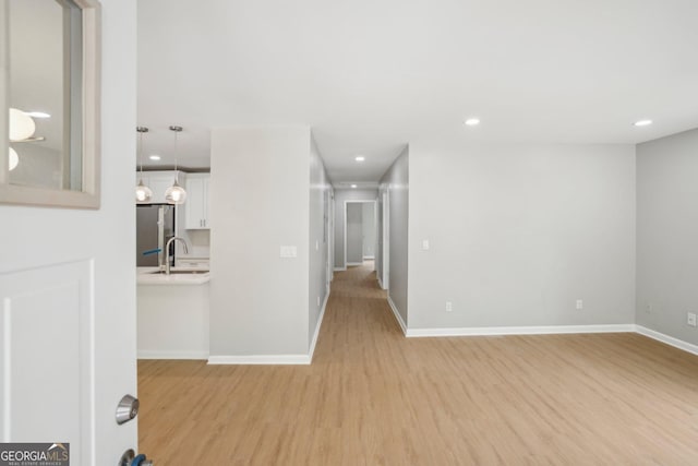 empty room featuring light wood-style floors, baseboards, recessed lighting, and a sink