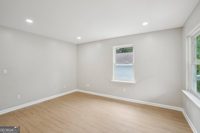 empty room with plenty of natural light, light wood finished floors, and recessed lighting