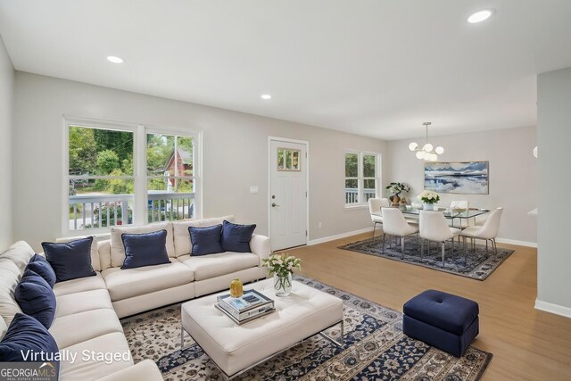 living room featuring a chandelier, wood finished floors, baseboards, and recessed lighting