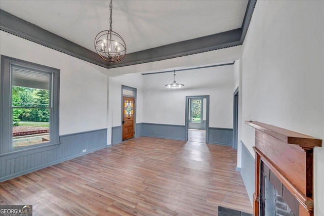 unfurnished room featuring a chandelier, wood finished floors, and a wainscoted wall