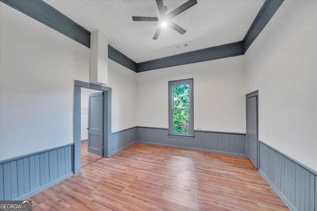 unfurnished room featuring a wainscoted wall, wood finished floors, and ceiling fan