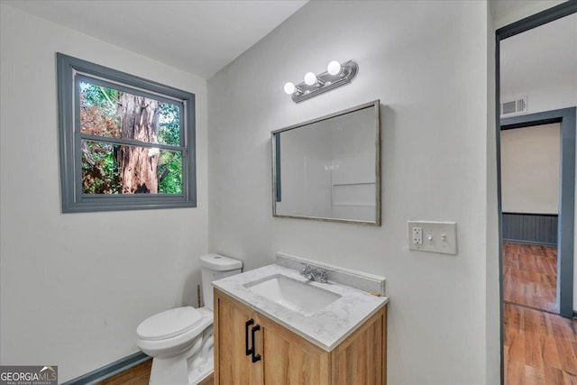 bathroom featuring toilet, wood finished floors, vanity, and baseboards