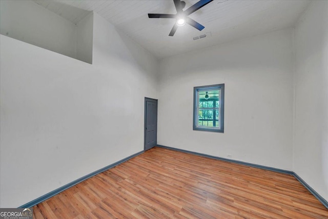 spare room featuring light wood finished floors, a ceiling fan, and baseboards