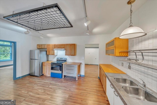 kitchen featuring appliances with stainless steel finishes, track lighting, a sink, baseboards, and light wood-style flooring