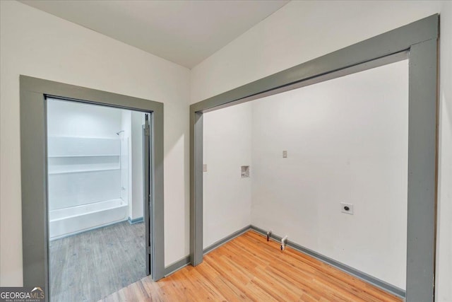 washroom featuring electric dryer hookup, light wood-style floors, and baseboards
