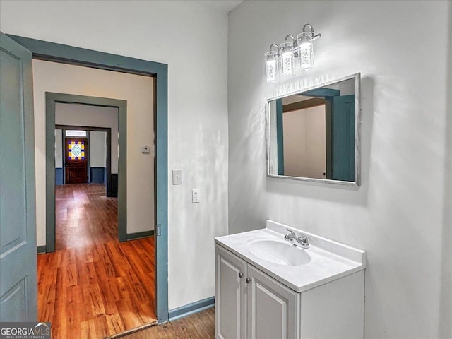 bathroom with wood finished floors, vanity, and baseboards