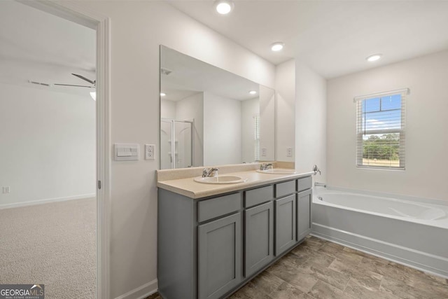 full bathroom with a bath, double vanity, recessed lighting, a stall shower, and baseboards