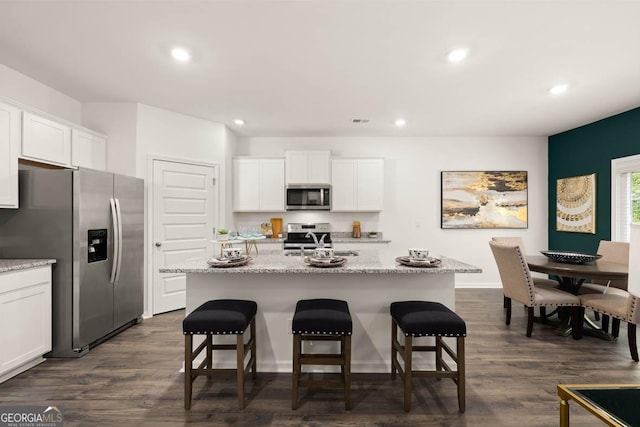 kitchen featuring appliances with stainless steel finishes, recessed lighting, a kitchen bar, white cabinets, and a kitchen island with sink