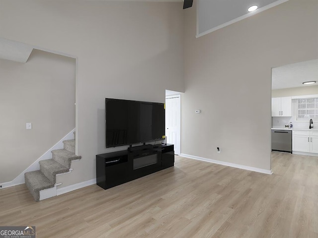 201 Twin Pines Ct, Dallas, GA 30132 - unfurnished living room with a towering ceiling, light wood finished floors, stairway, and baseboards