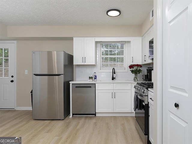 201 Twin Pines Ct, Dallas, GA 30132 - kitchen with appliances with stainless steel finishes, light wood-style floors, a sink, white cabinetry, and a textured ceiling