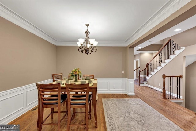 5000 Davenport Pl, Roswell, GA 30075 - dining area featuring crown molding, a chandelier, stairs, wood finished floors, and a decorative wall