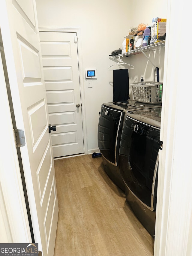 clothes washing area with light wood-type flooring, washer and clothes dryer, and baseboards