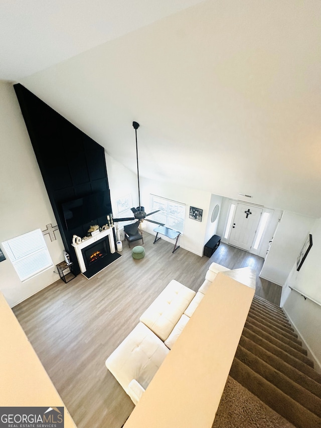living area with wood finished floors, a lit fireplace, and stairs