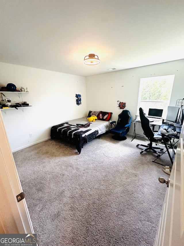 carpeted bedroom featuring an office area and baseboards