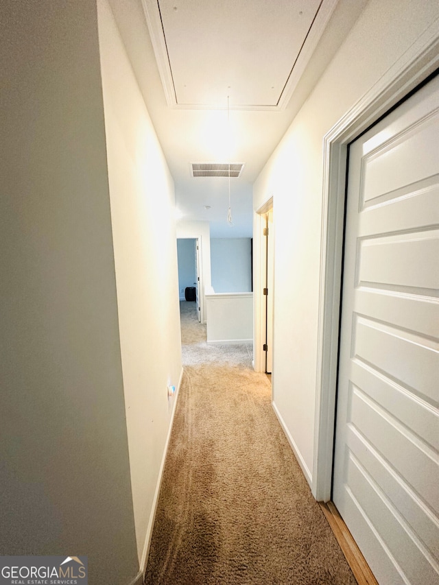 corridor with attic access, carpet floors, and baseboards