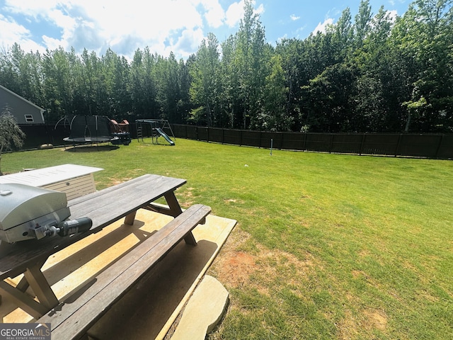 view of yard featuring a trampoline, a playground, and outdoor dining space