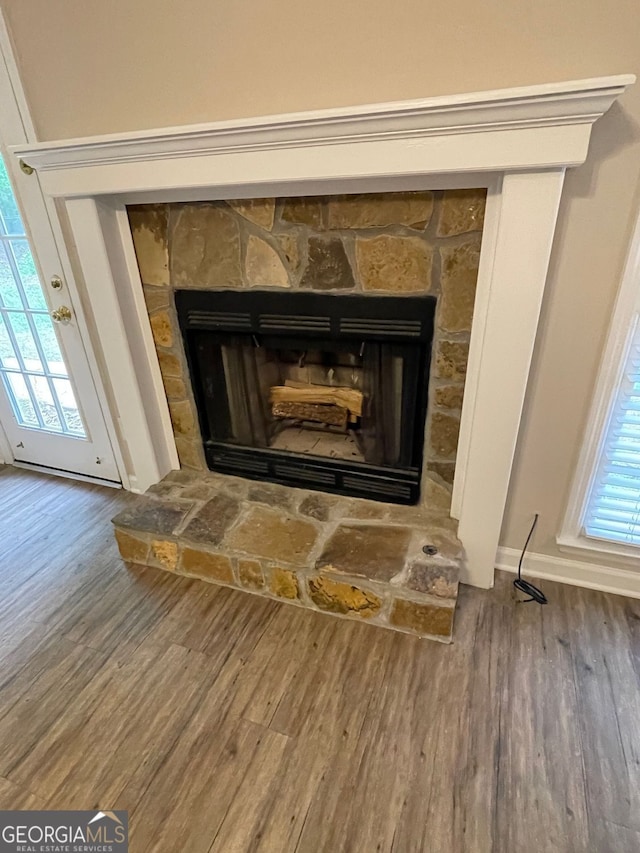 detailed view of wood finished floors, a fireplace, and baseboards