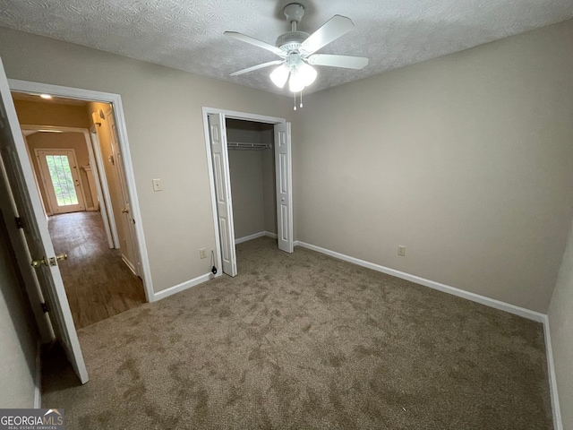 unfurnished bedroom with carpet floors, baseboards, a closet, a textured ceiling, and a ceiling fan