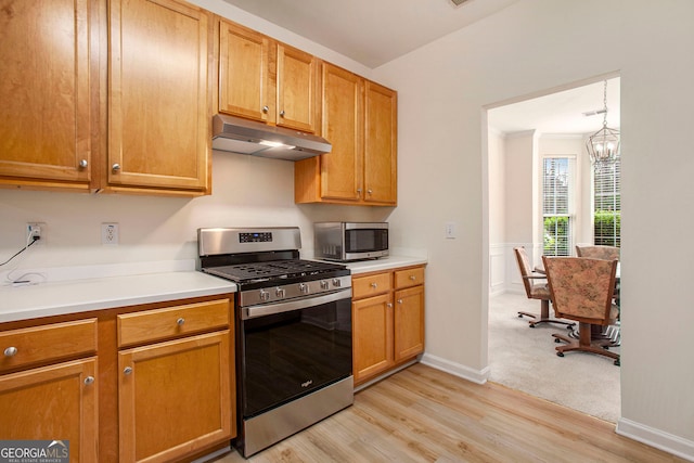 4535 Howell Farms Rd NW, Acworth, GA 30101 - kitchen with under cabinet range hood, stainless steel appliances, light countertops, a chandelier, and a wainscoted wall