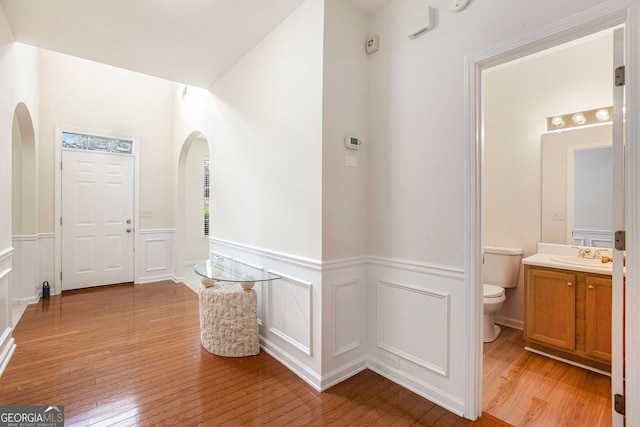 4535 Howell Farms Rd NW, Acworth, GA 30101 - corridor featuring arched walkways, a sink, light wood-type flooring, wainscoting, and a decorative wall