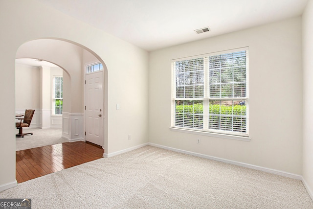 4535 Howell Farms Rd NW, Acworth, GA 30101 - carpeted empty room with arched walkways, plenty of natural light, hardwood / wood-style flooring, and a wainscoted wall