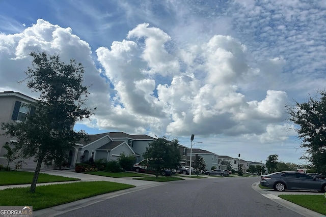 view of asphalt street with a residential view, street lights, and curbs
