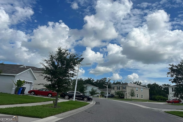 view of asphalt road with street lighting, a residential view, sidewalks, and curbs