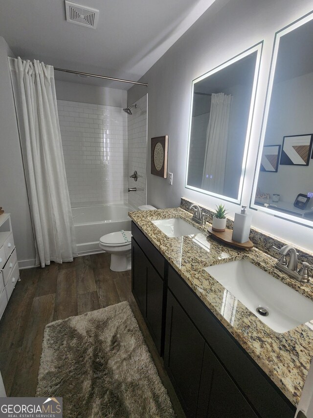 bathroom with wood finished floors, shower / bath combo, toilet, and double vanity