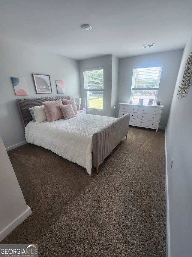 bedroom with dark carpet and baseboards