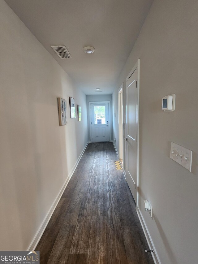 hall with dark wood-style flooring and baseboards