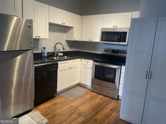20 Marietta St NW Unit 10F, Atlanta, GA 30303 - kitchen featuring appliances with stainless steel finishes, a sink, dark countertops, dark wood-style flooring, and white cabinetry