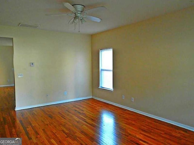 unfurnished room with ceiling fan, wood finished floors, and baseboards