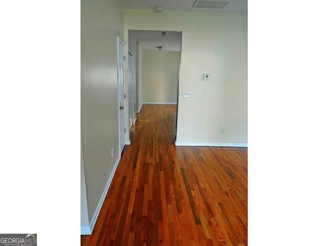 corridor featuring baseboards and wood finished floors