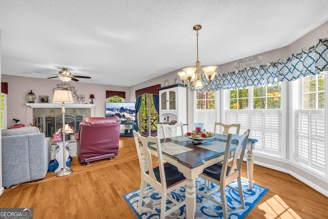 1886 Bend N Hickory Rd, Toccoa, GA 30577 - dining area featuring a chandelier, a textured ceiling, light wood-style floors, ceiling fan, and a stone fireplace