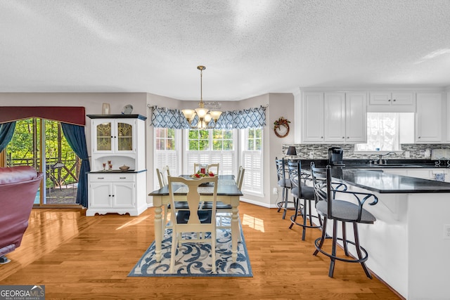 1886 Bend N Hickory Rd, Toccoa, GA 30577 - dining space featuring a chandelier, a textured ceiling, plenty of natural light, and light wood-style floors