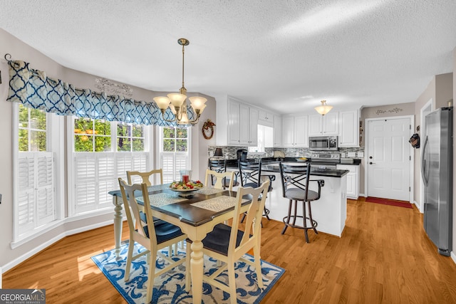 1886 Bend N Hickory Rd, Toccoa, GA 30577 - dining area featuring a textured ceiling, plenty of natural light, light wood-style floors, a chandelier, and baseboards