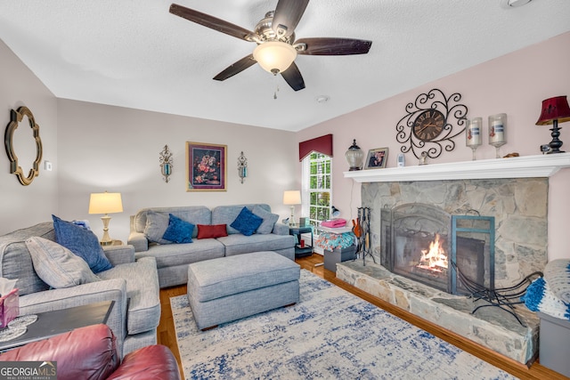 1886 Bend N Hickory Rd, Toccoa, GA 30577 - living area featuring a fireplace, wood finished floors, a textured ceiling, and a ceiling fan