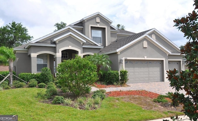 view of front facade with an attached garage, a front yard, stucco siding, and driveway