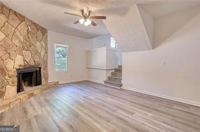 3959 Wood Path Dr, Stone Mountain, GA 30083 - unfurnished living room with a textured ceiling, ceiling fan, wood finished floors, stairs, and a fireplace