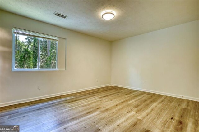 spare room with wood finished floors, baseboards, and a textured ceiling