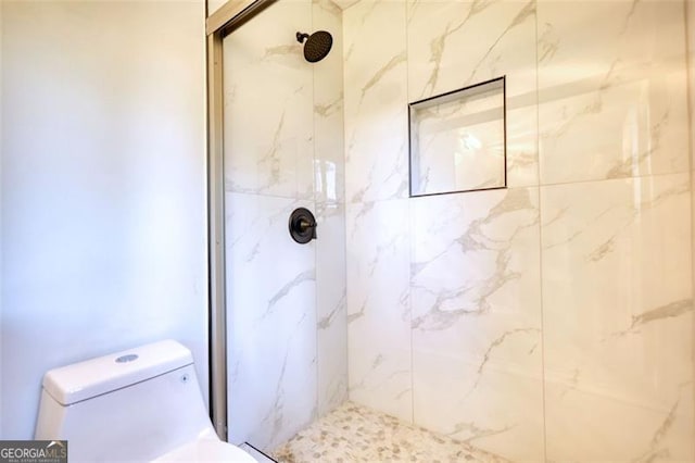 bathroom with a marble finish shower and toilet