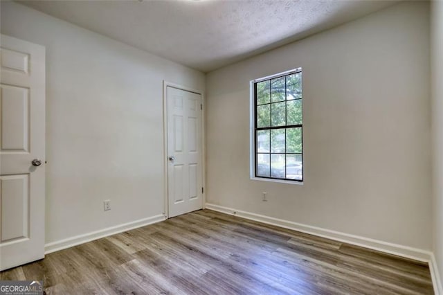 unfurnished bedroom featuring wood finished floors and baseboards