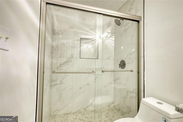 full bath featuring toilet and a marble finish shower