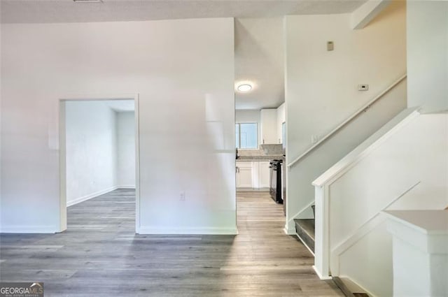 foyer entrance featuring stairway, light wood-style floors, and baseboards