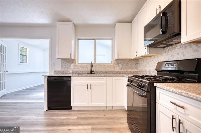 3959 Wood Path Dr, Stone Mountain, GA 30083 - kitchen with black appliances, light wood-style flooring, white cabinets, and tasteful backsplash
