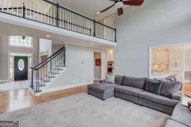 1608 Mulberry Lake Dr, Dacula, GA 30019 - living room featuring a towering ceiling, ceiling fan, wood finished floors, stairs, and baseboards