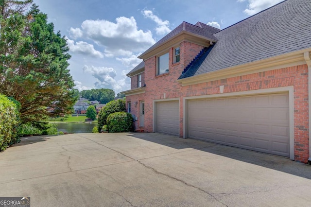 1608 Mulberry Lake Dr, Dacula, GA 30019 - view of home's exterior featuring brick siding, concrete driveway, a shingled roof, and a water view