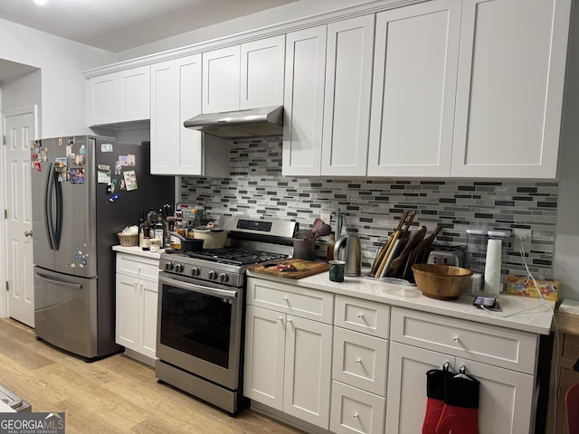 kitchen with appliances with stainless steel finishes, under cabinet range hood, light wood-style floors, and light countertops
