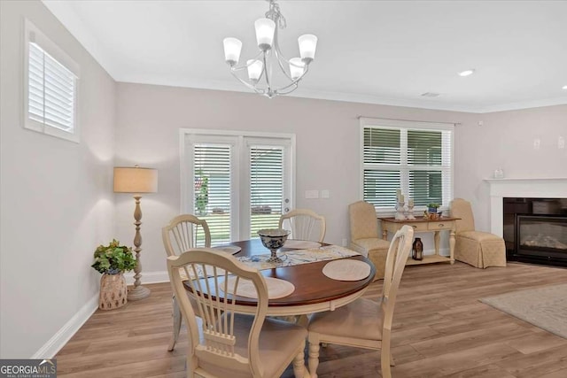 427 Bluffs View Ln, Canton, GA 30114 - dining space with a chandelier, light wood finished floors, baseboards, a glass covered fireplace, and ornamental molding